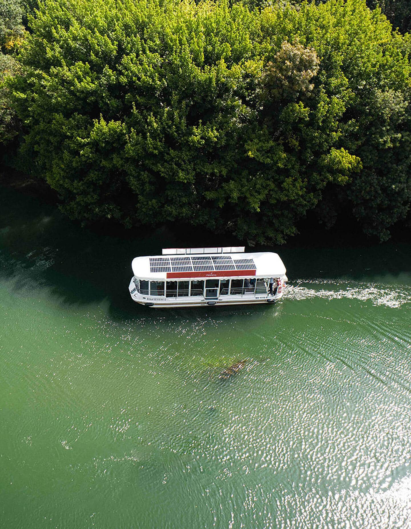 Hennessy solar-powered boat cruising along the Charente River in Cognac, amidst pristine greenery