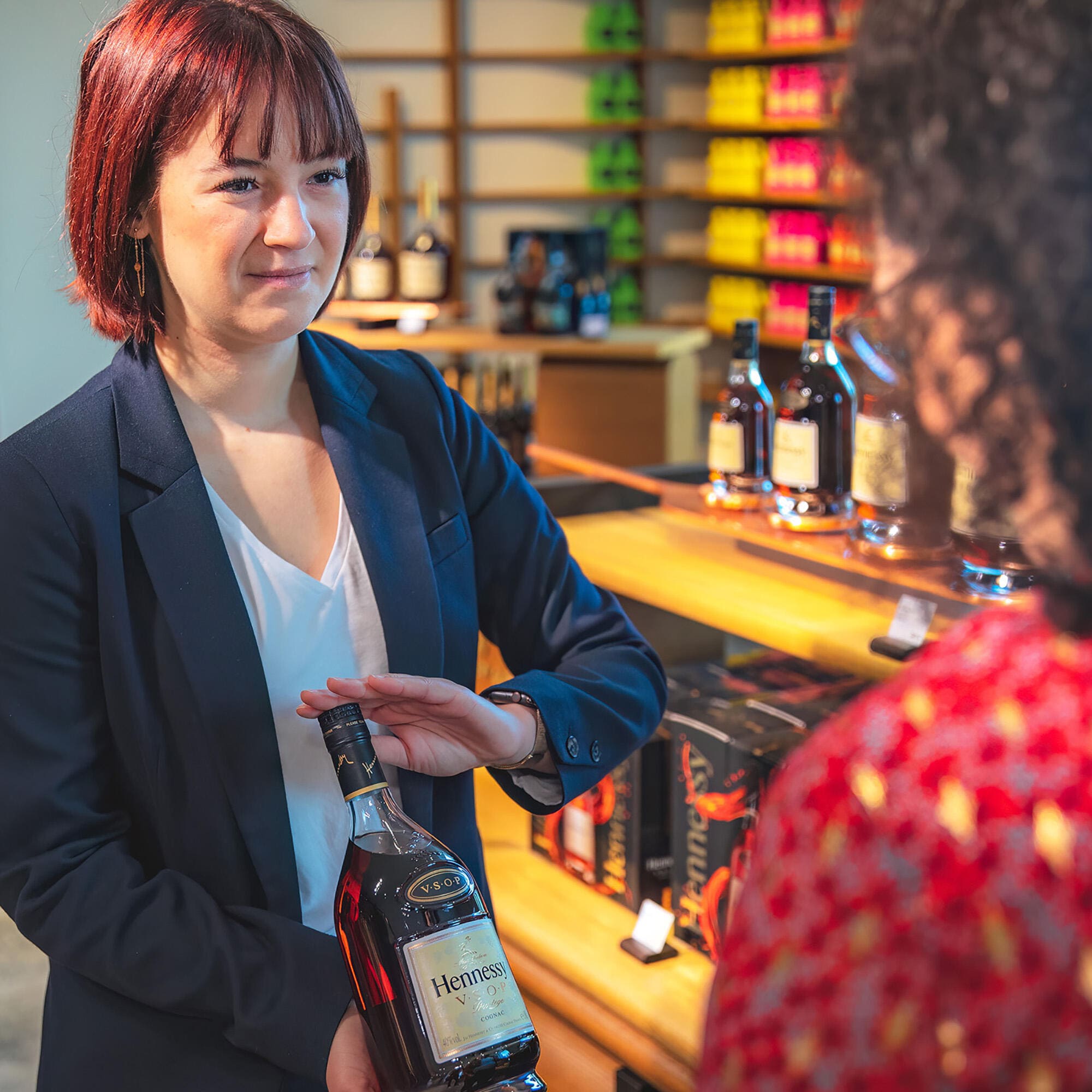 A sales attendant showing a bottle of Hennessy VSOP to a customer
