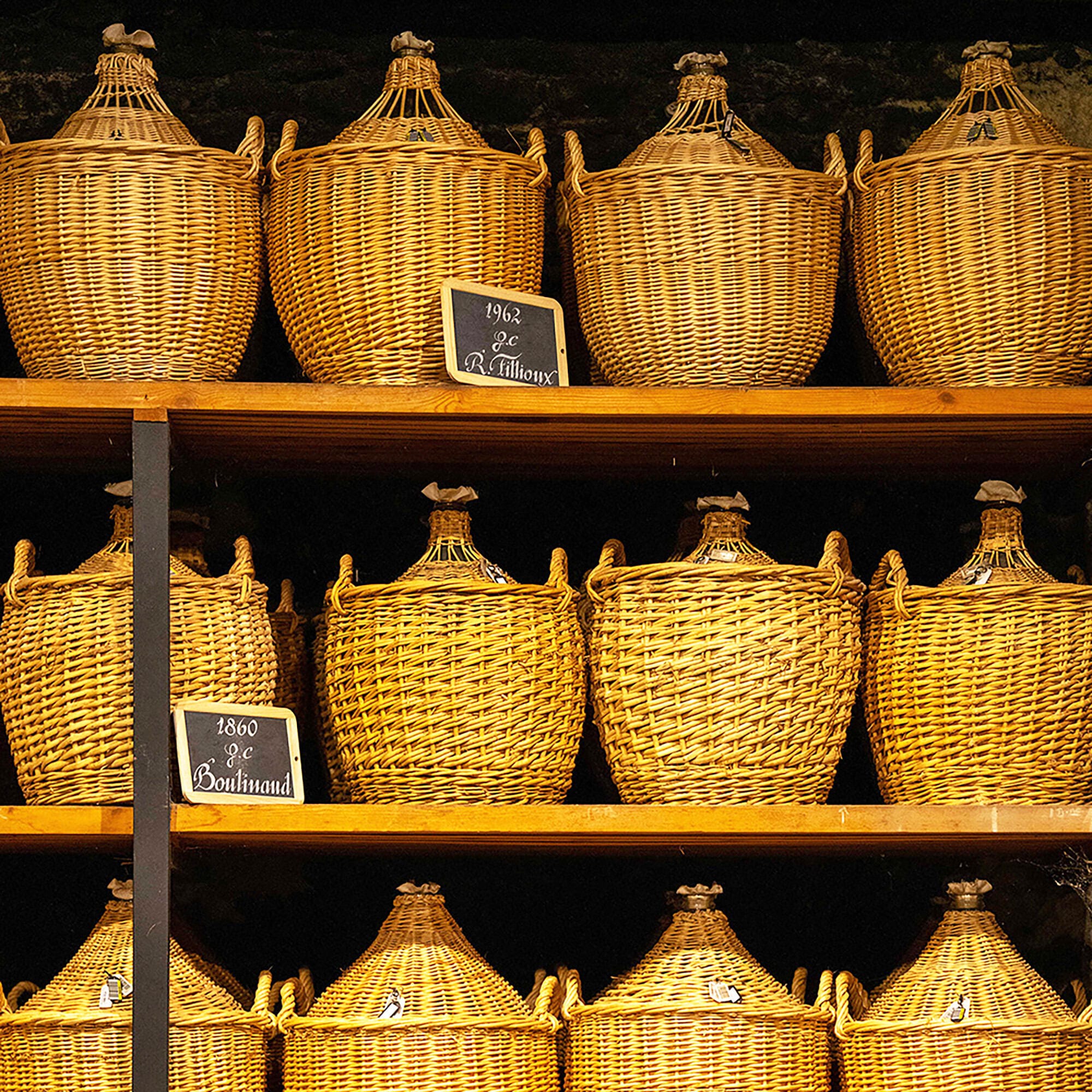 Rows of glass demi-johns on shelves in Hennessy's historical Paradis Cellar, holding very old eaux-de-vie