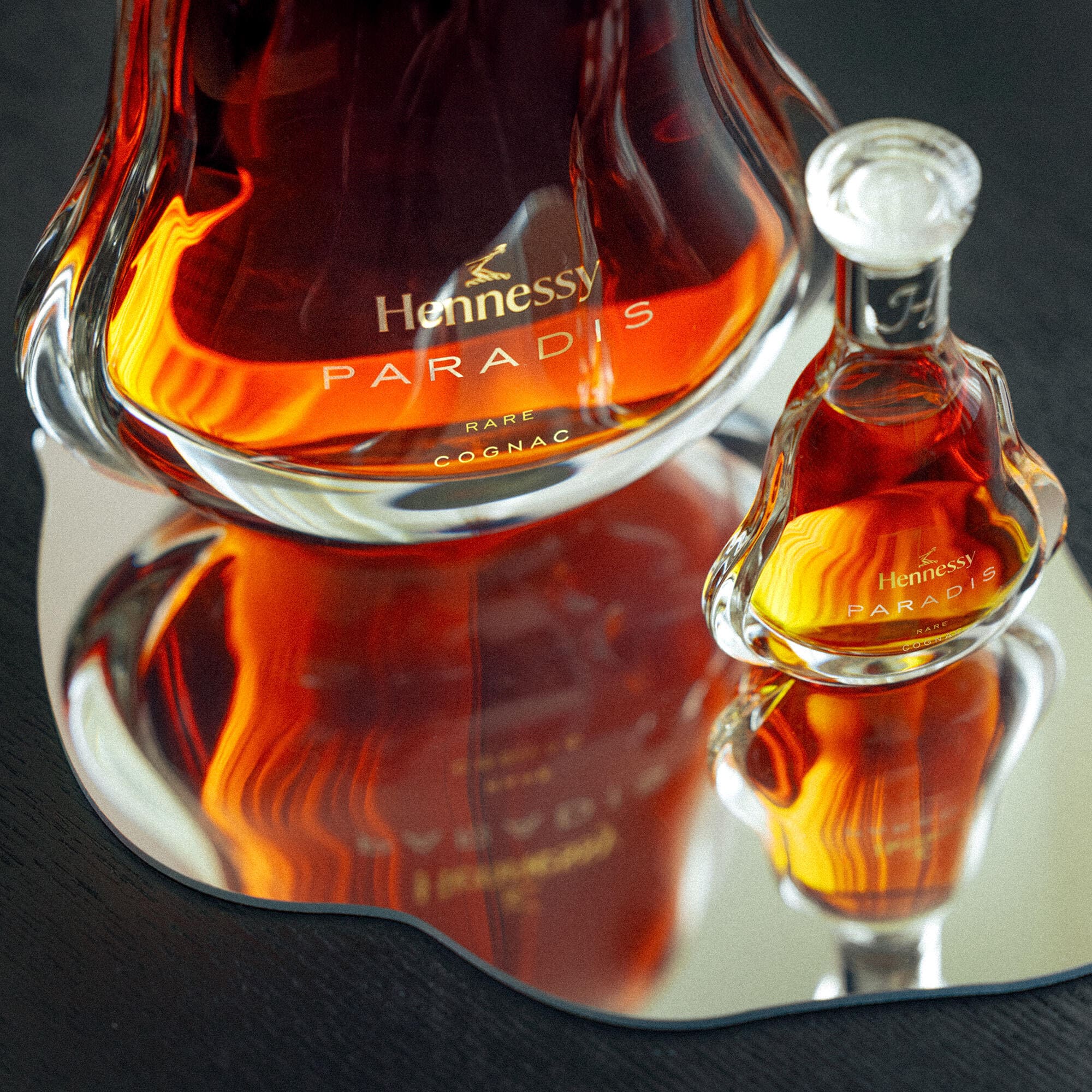 A decanter of Hennessy Paradis upgrade 70cl on a coffee table, next to a bottle of Paradis Mini 5cl